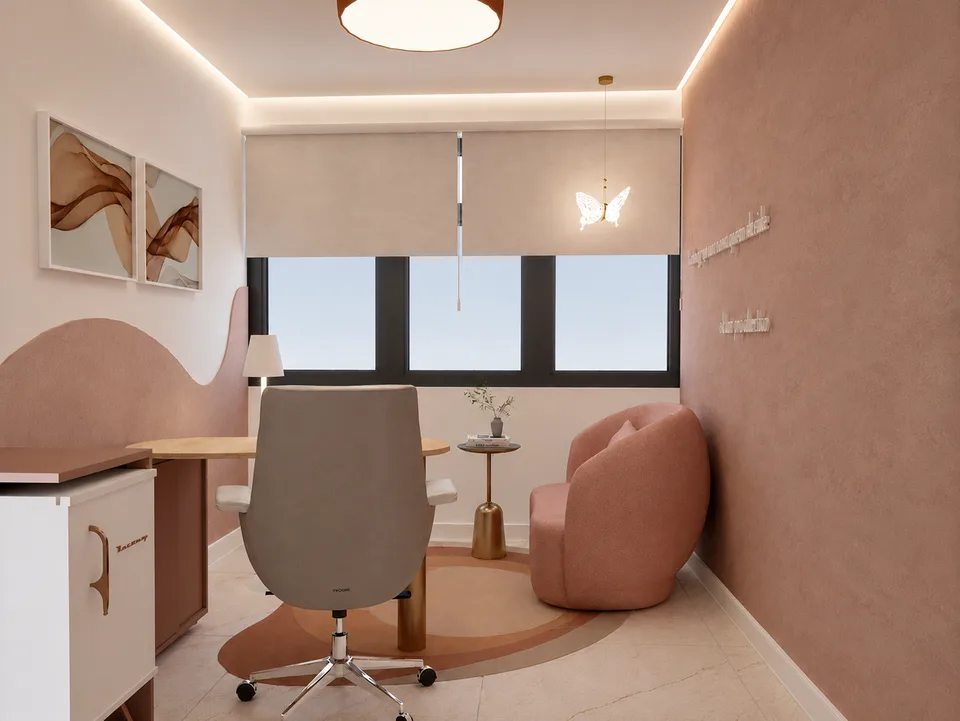 Espaço Florescer: mesa de trabalho em madeira, cadeira de escritório e poltrona rosé junto à janela.