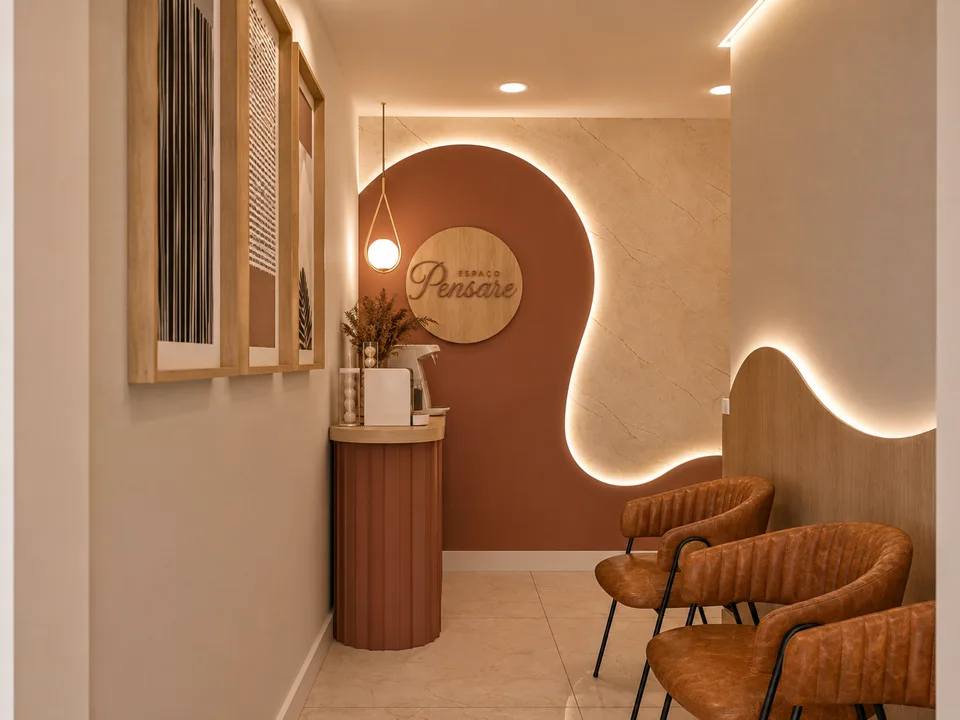 Sala de espera do Espaço Pensare com poltronas de couro caramelo e logotipo em madeira na parede.